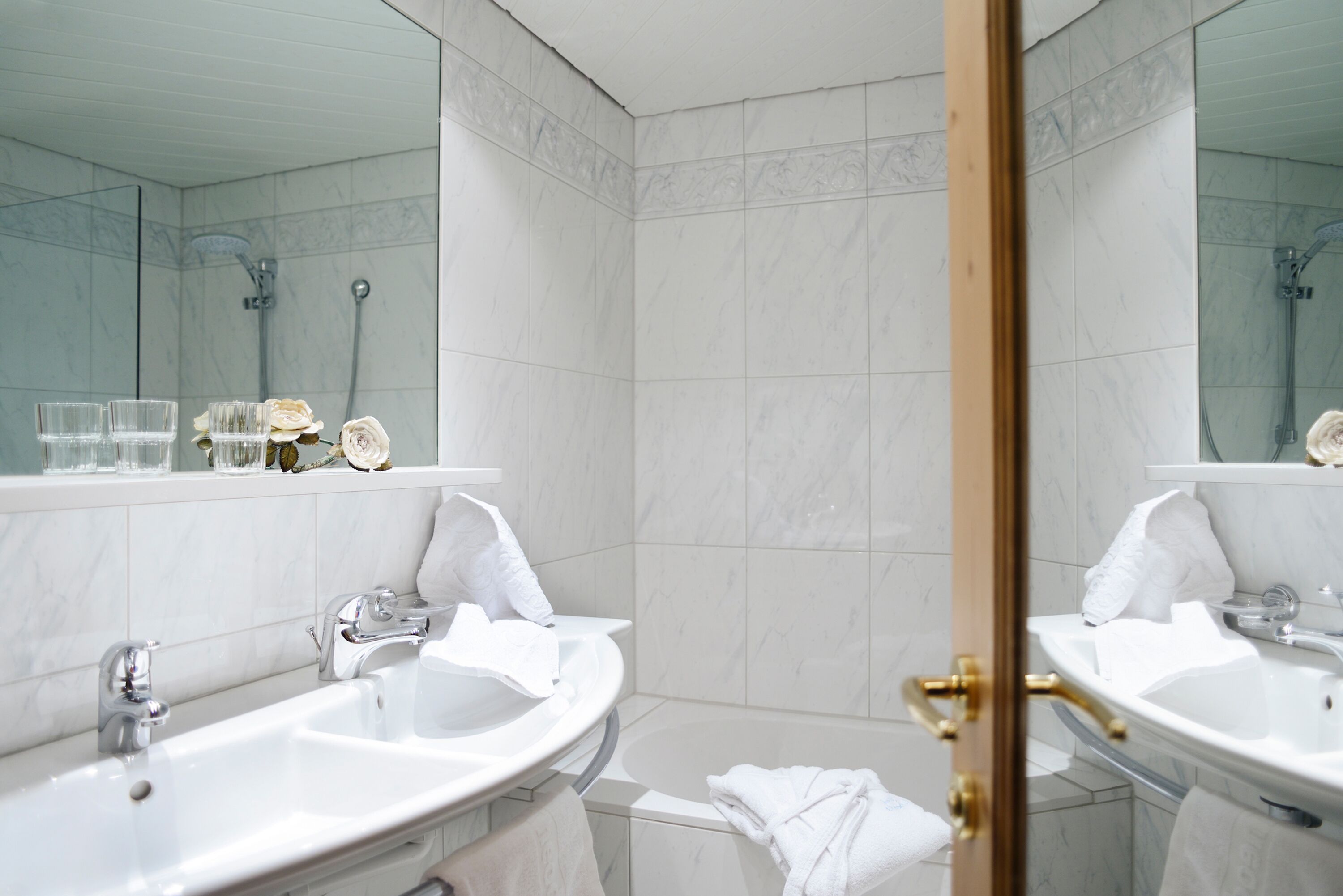 A modern bathroom with two sinks, a shower, and a large mirror.