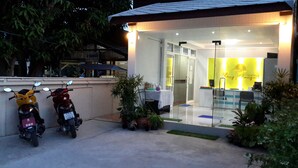 Un edificio con recepción, puerta de vidrio y dos motocicletas estacionadas.