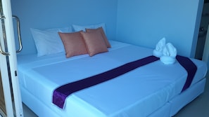 Una camera d'albergo con un letto, cuscini, un asciugamano e una coperta viola.