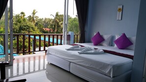 A hotel room with a balcony, a bed with white bedding and purple pillows, and a view of palm trees and a pool. - Rung Phangan Hotel (Ko Pha-ngan)