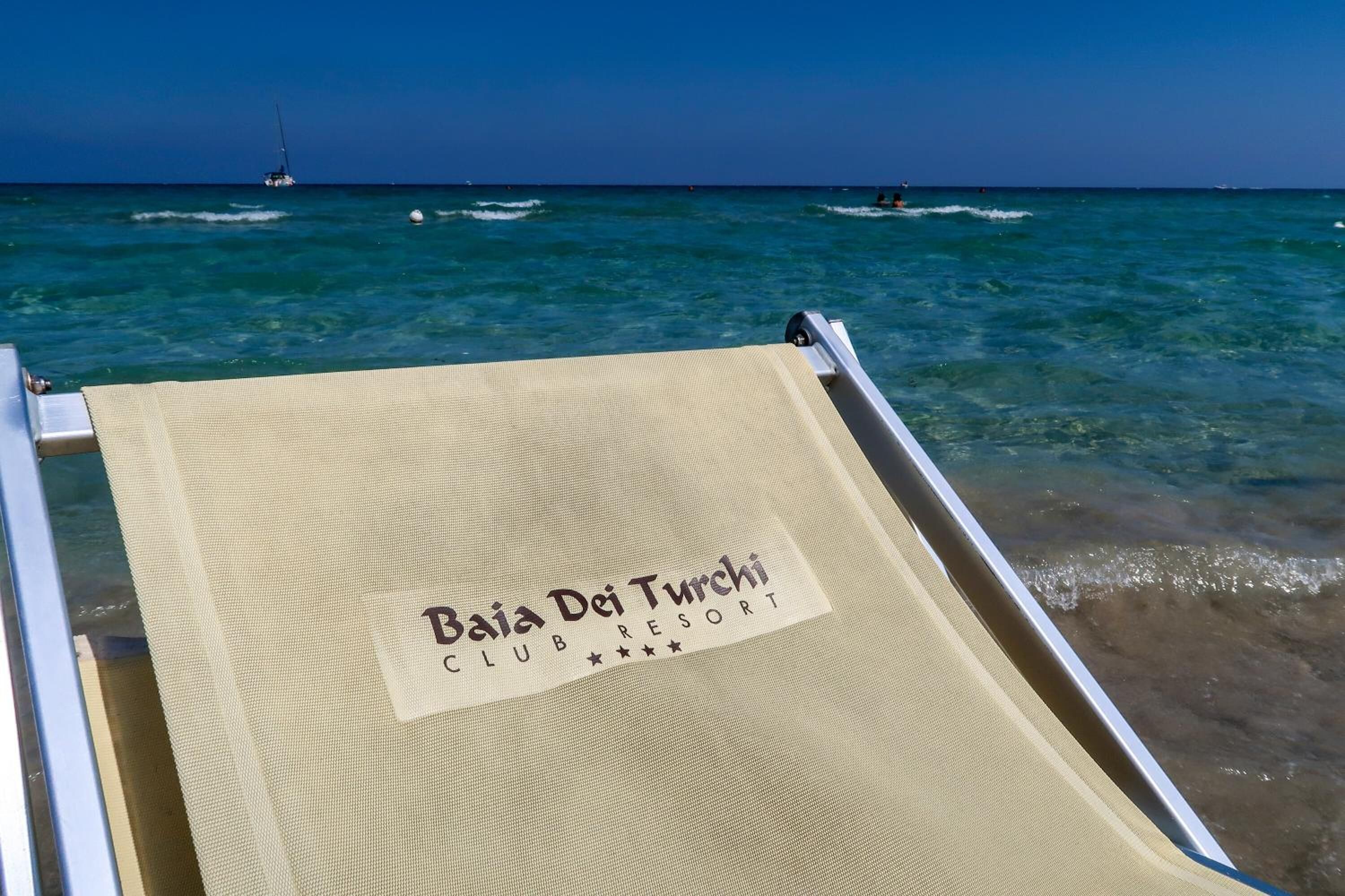 En strandstol med en etikett där det står: ”Baja Dei Turci CLUB RESORT”.
