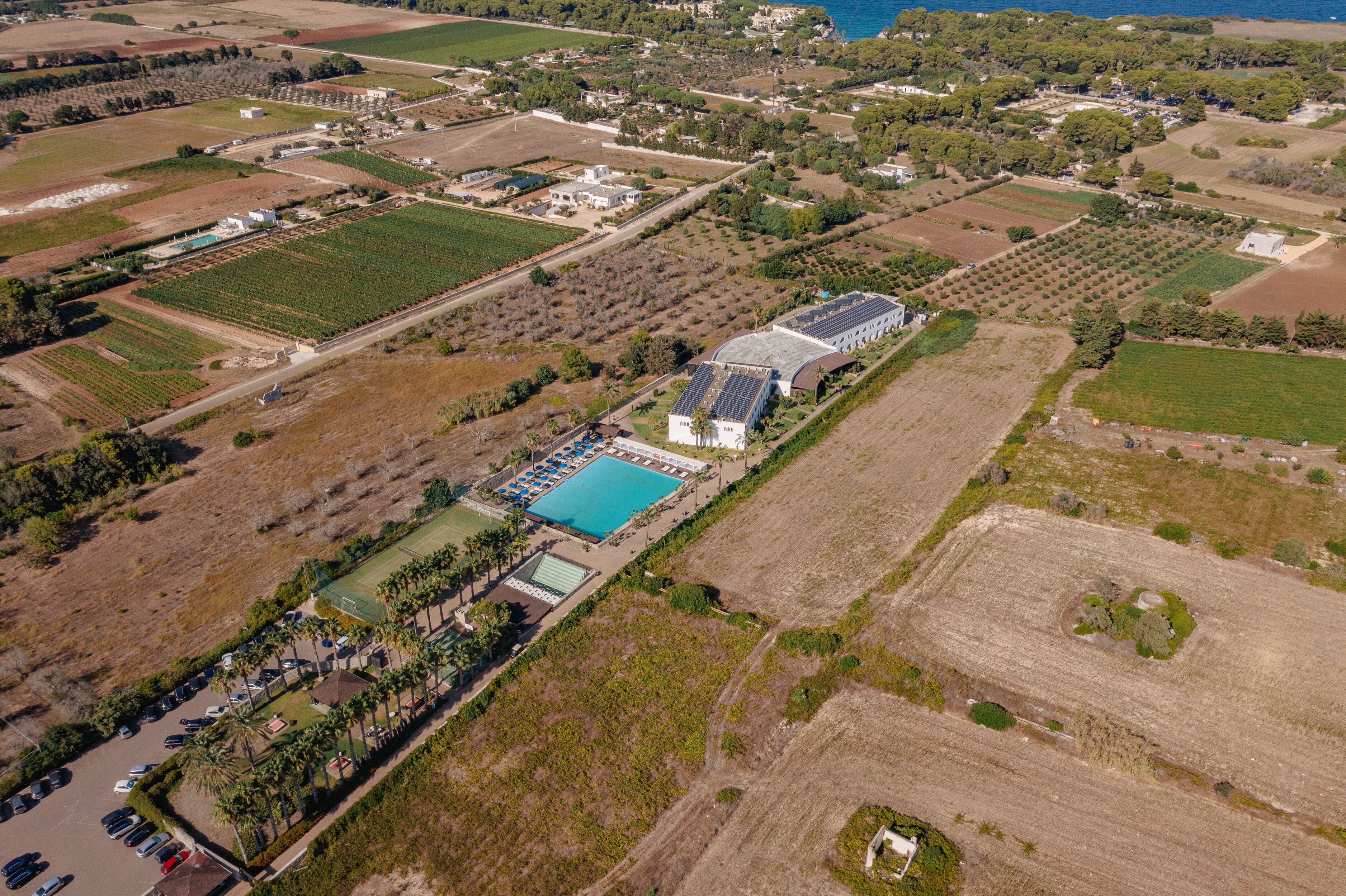An aerial view of a resort with a swimming pool, solar panels, and various buildings.