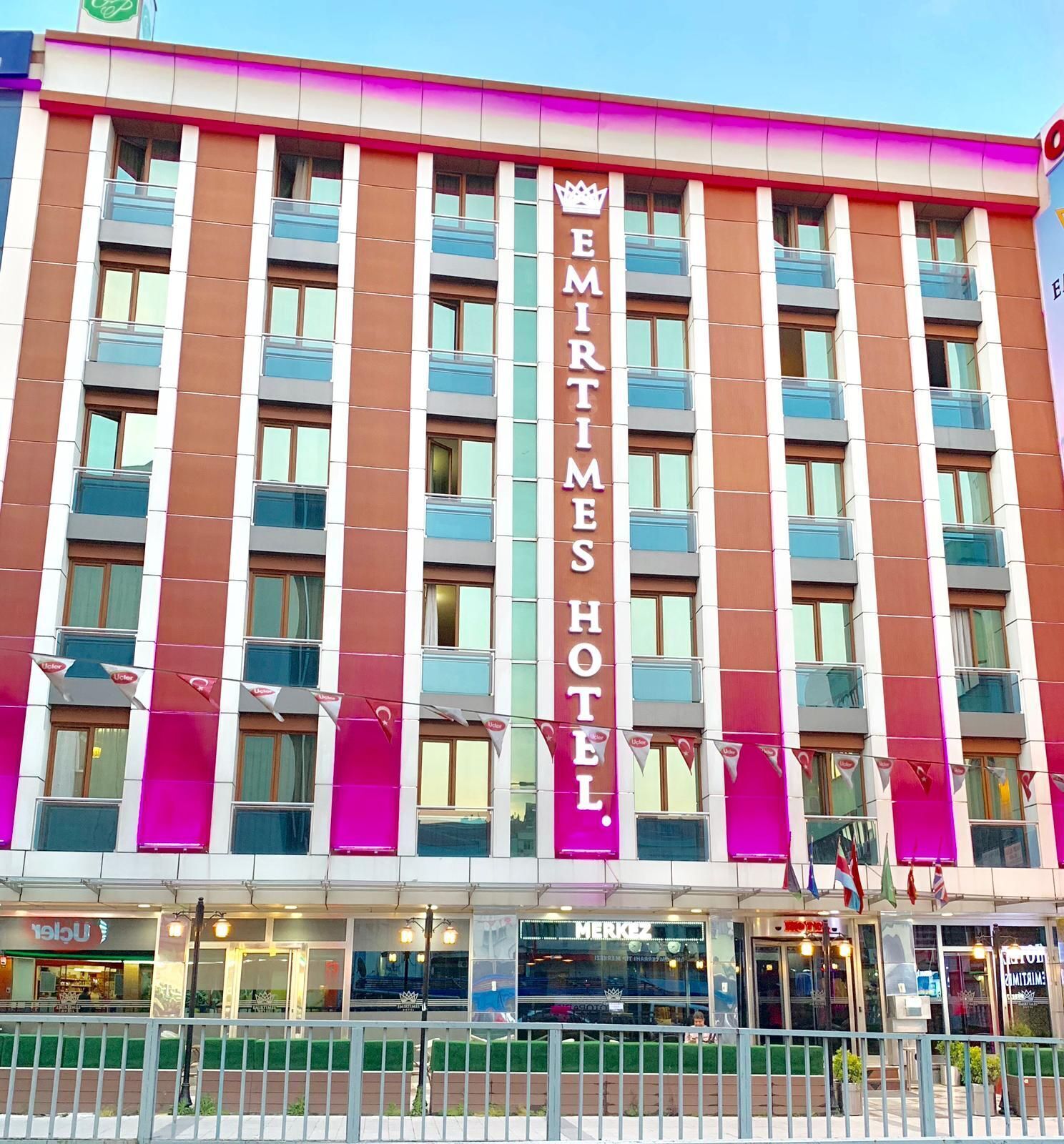 A hotel with a prominent vertical sign reading "EMIRTIMES HOTEL" and a crown symbol.