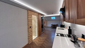 A modern kitchen with a herringbone floor, wooden cabinetry, and a white countertop. - Gumus Palace Hotel (Istanbul)