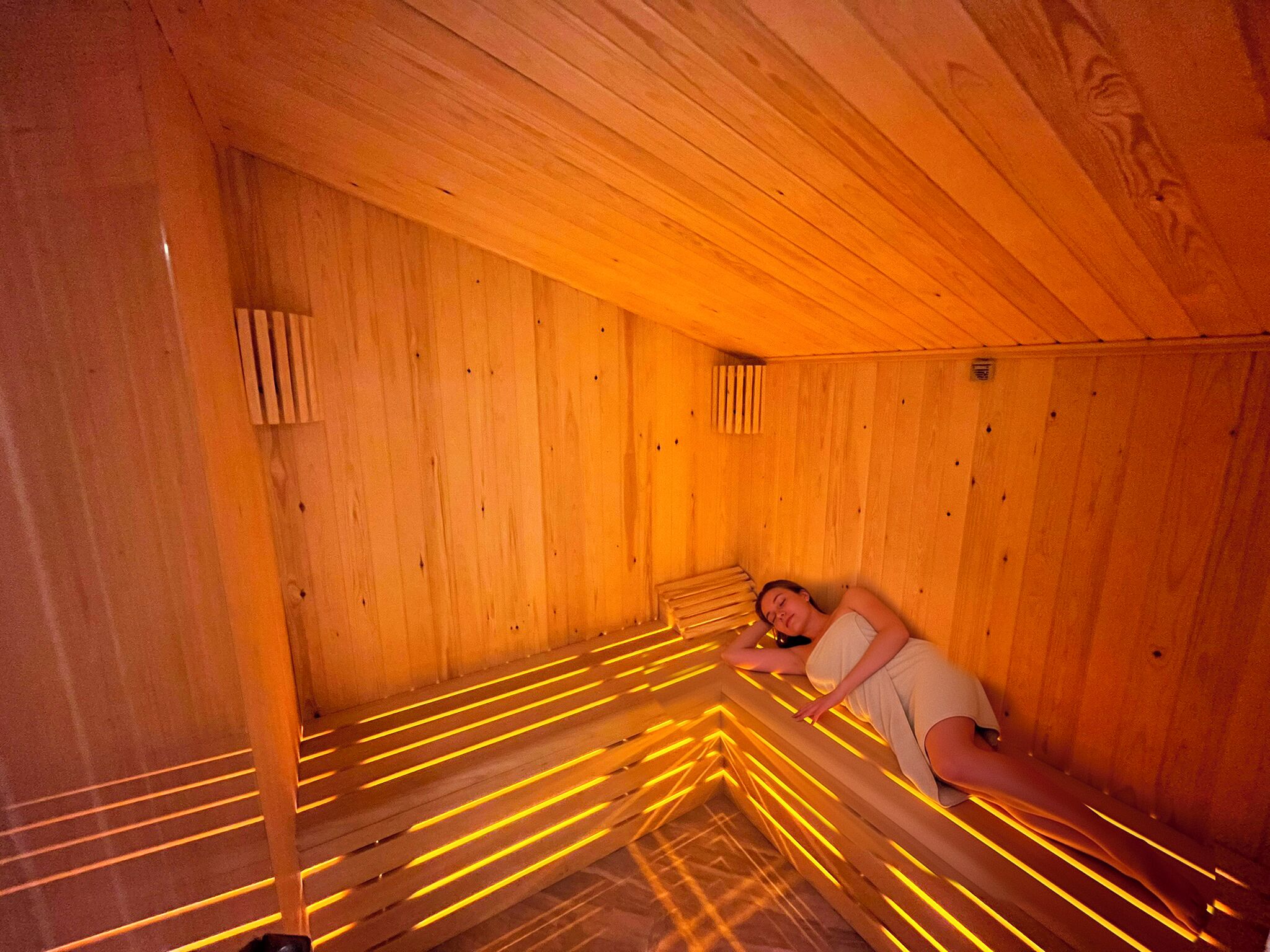 A wooden sauna with slatted benches and warm lighting.