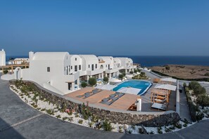 Et resort med hvide bygninger, en swimmingpool og havudsigt.