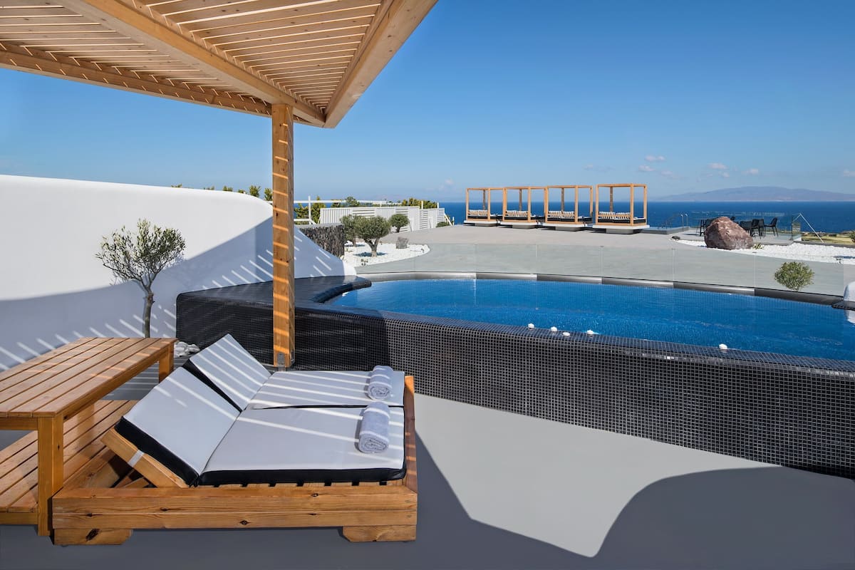 A poolside area with lounge chairs and a pergola, overlooking a clear blue sky and a distant view of the sea.