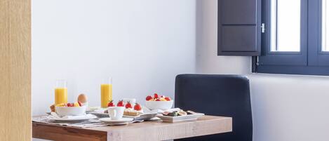 A dining area with a table set for breakfast, a chair, and a window with shutters.