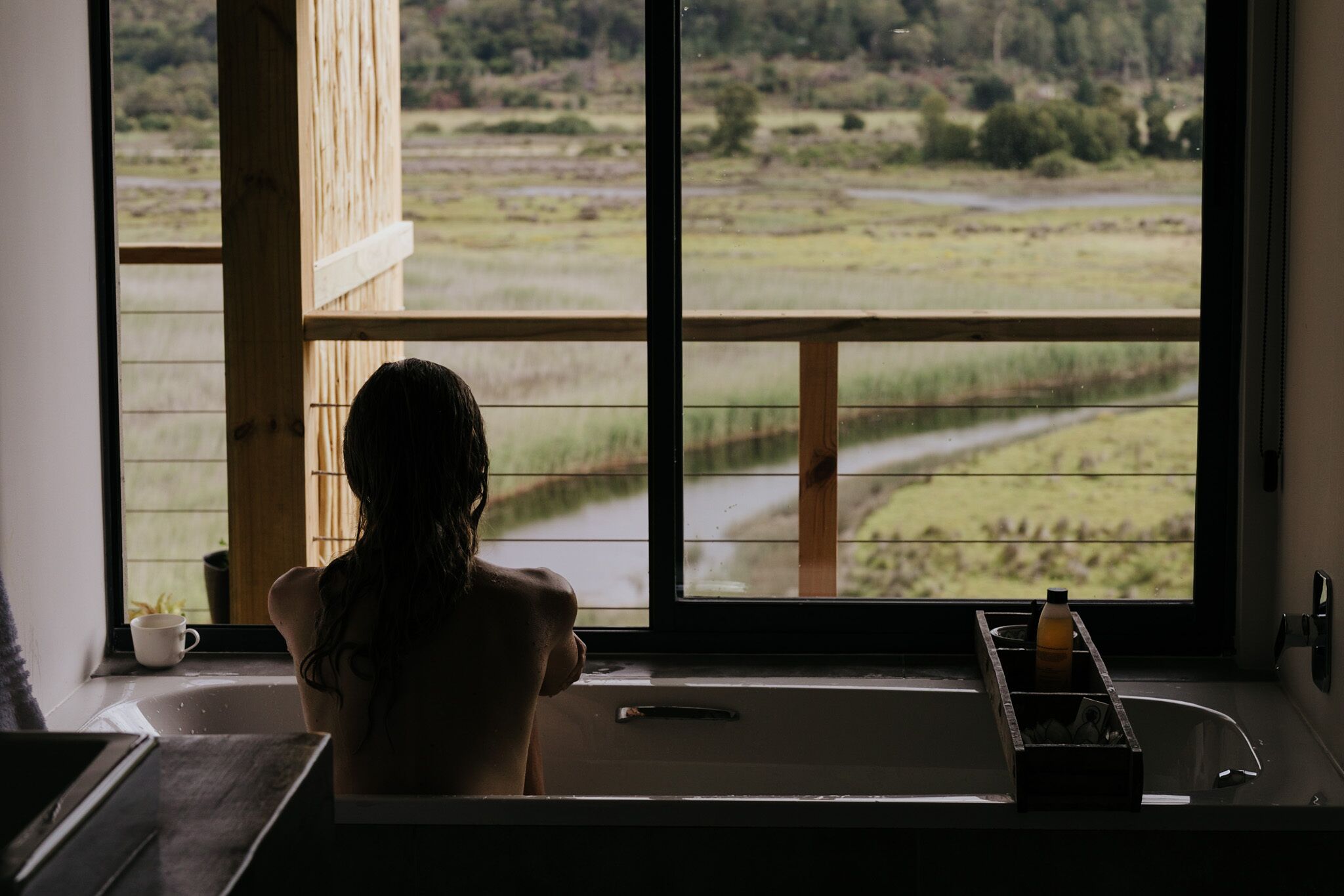 Een badkamer met een groot raam en uitzicht op het omliggende platteland.