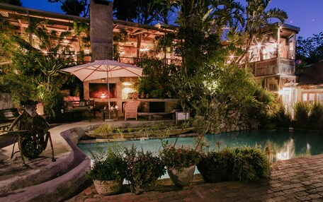 A poolside area with a barbecue setup, outdoor seating, and a stone wall.