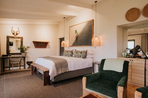 Un dormitorio con cama, una silla, un escritorio, un espejo y un cuadro.