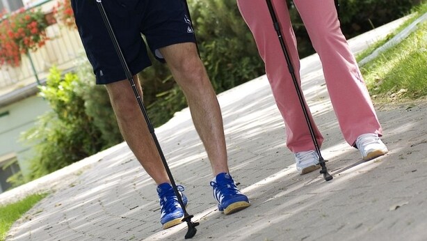 Two people walking on a sidewalk, one holding a walking stick and the other holding a cane. - Hotel Spa Hévíz (Hévíz)