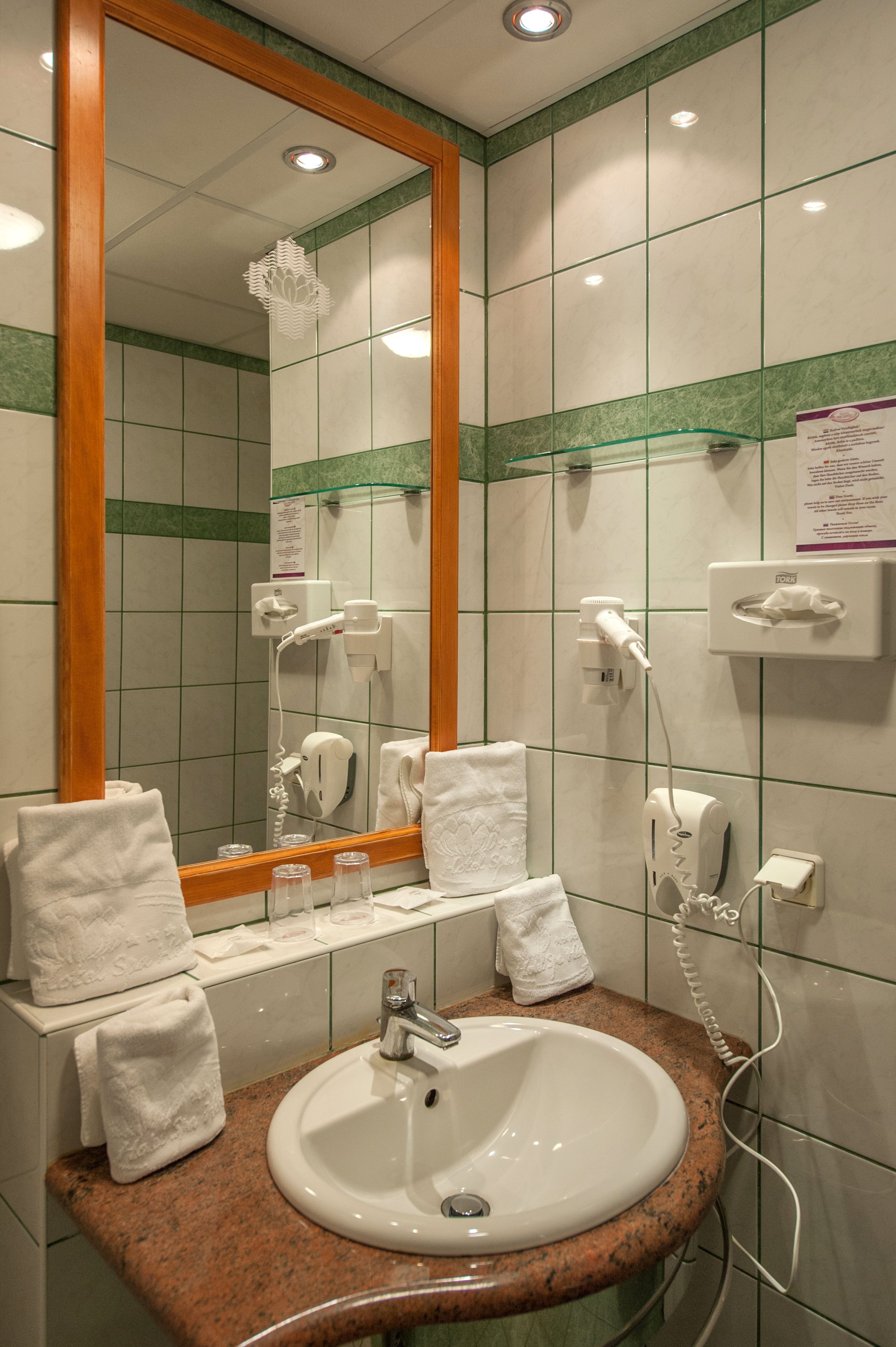 Ein Badezimmer mit Waschbecken, Spiegel, Handtuchhalter und Pflegeprodukten.