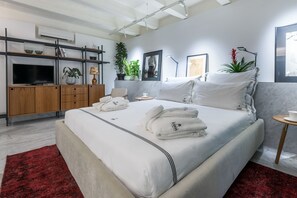 Una habitación de hotel moderna con una cama grande, un televisor, un escritorio y una alfombra roja.