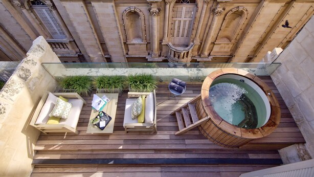 Une terrasse sur le toit dotée d’un jacuzzi, de sièges en bois et d’une balustrade en verre.