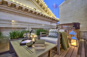An outdoor seating area with a wooden table, cushions, and a lantern. - Casa Ellul - Small Luxury Hotels of the World (Valletta)