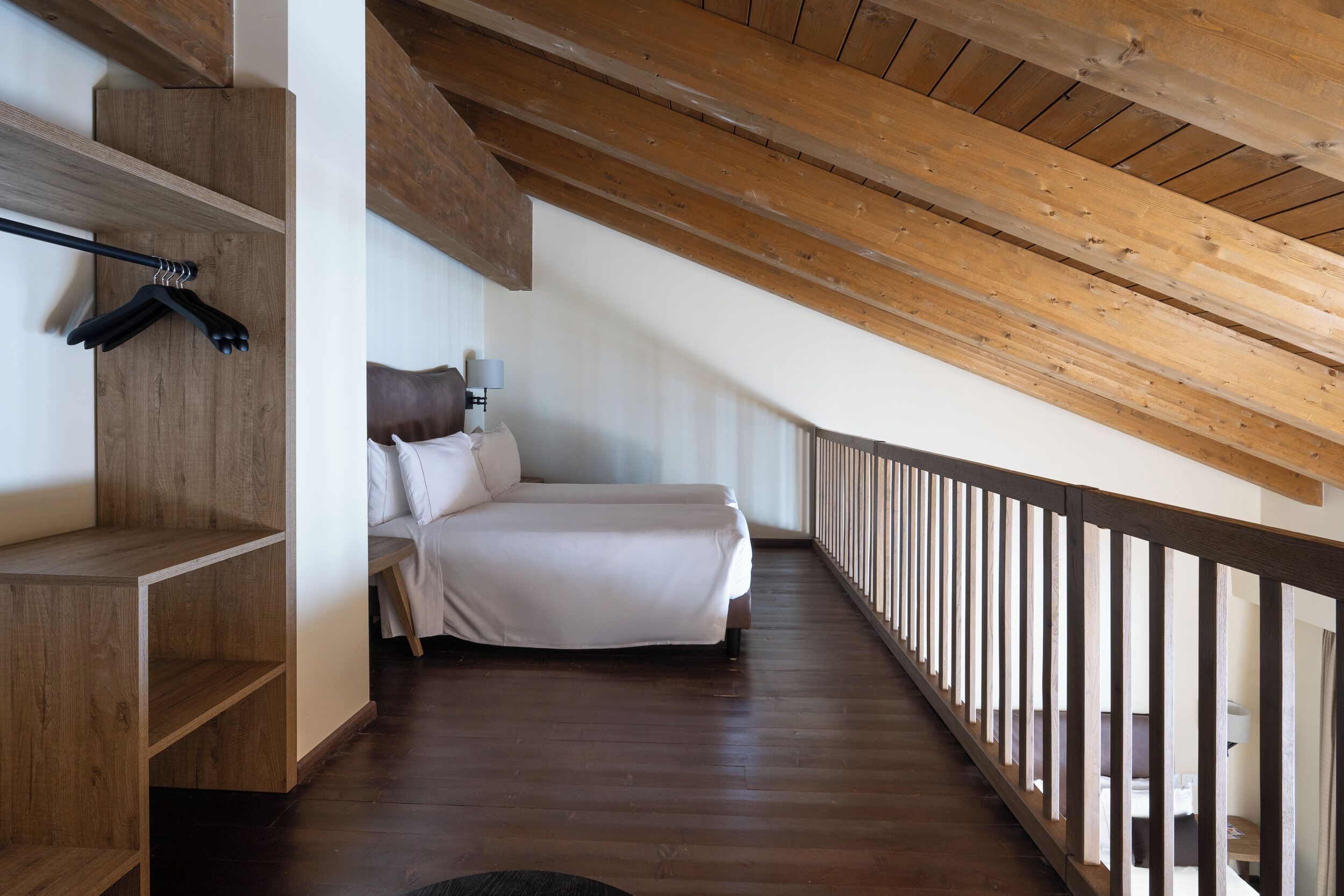 A bedroom with a wooden ceiling, a bed, a nightstand, and a wooden shelf unit.