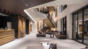 A spacious lobby with a reception desk, a staircase, and seating areas. - Grand Hotel Courmayeur Montblanc by R Collection Hotels (Courmayeur)