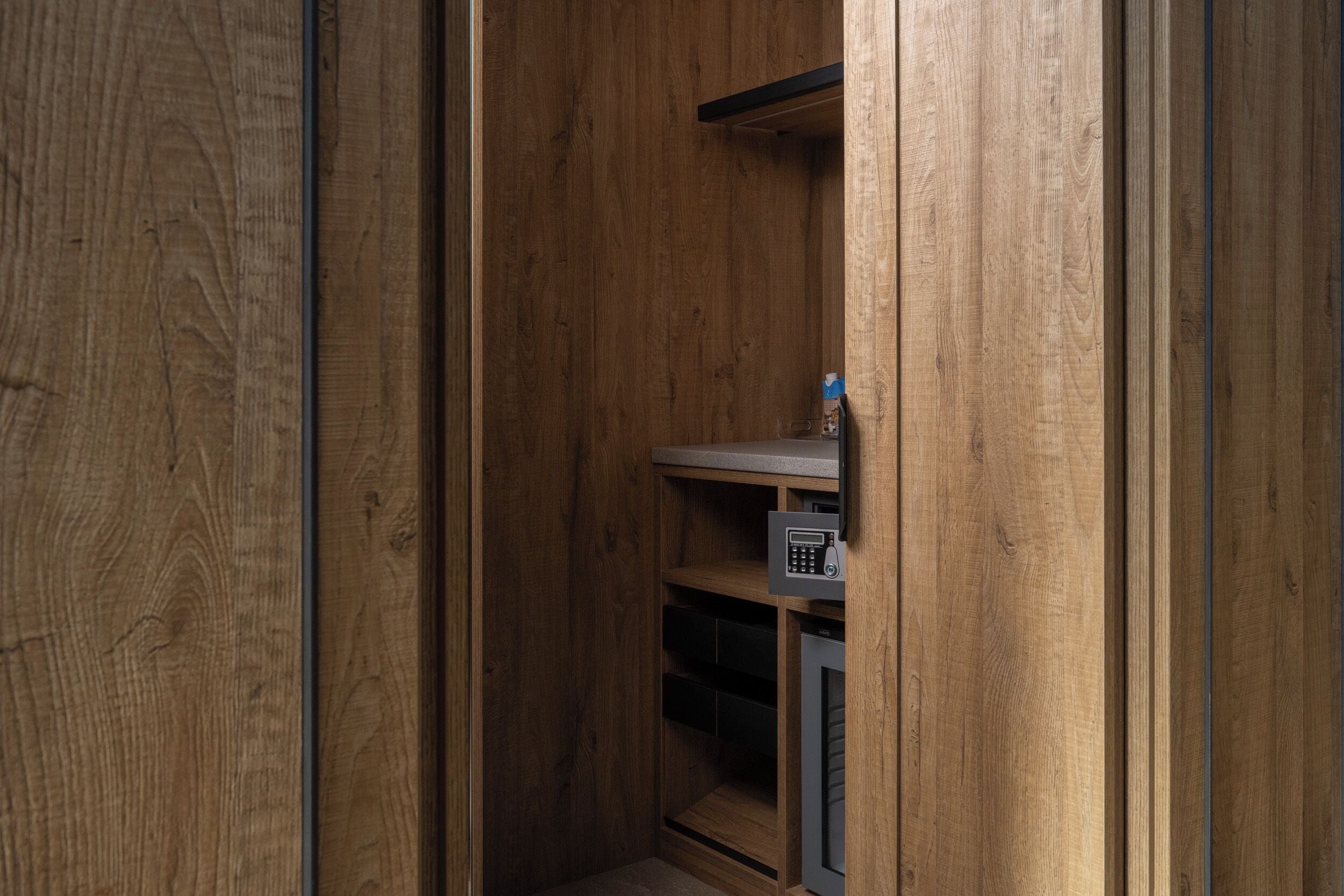 A wooden interior with a built-in safe, a shelf, and a small cabinet.