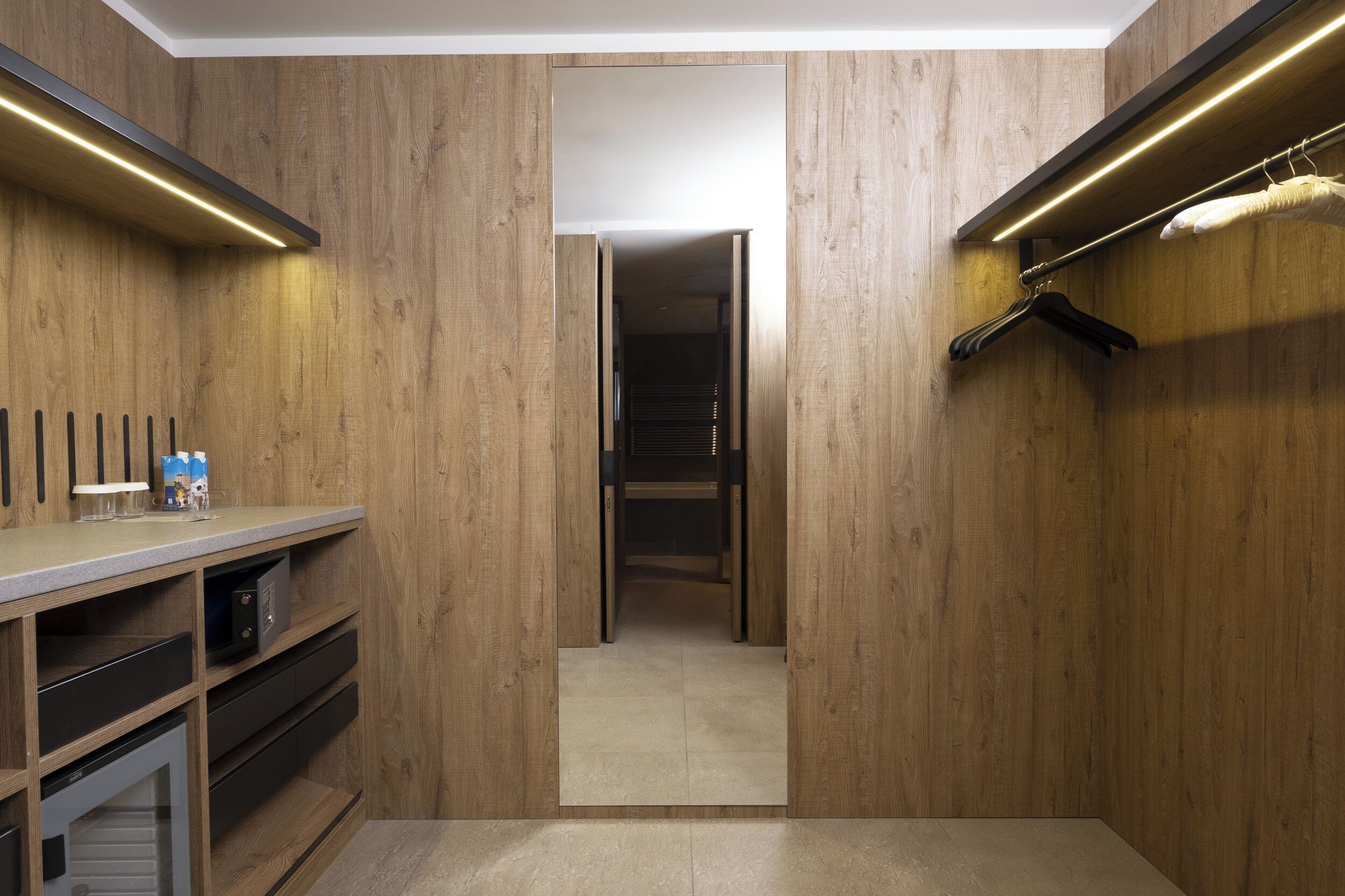 A modern bathroom with wooden walls, a mirror, a towel rack, and a shower area.