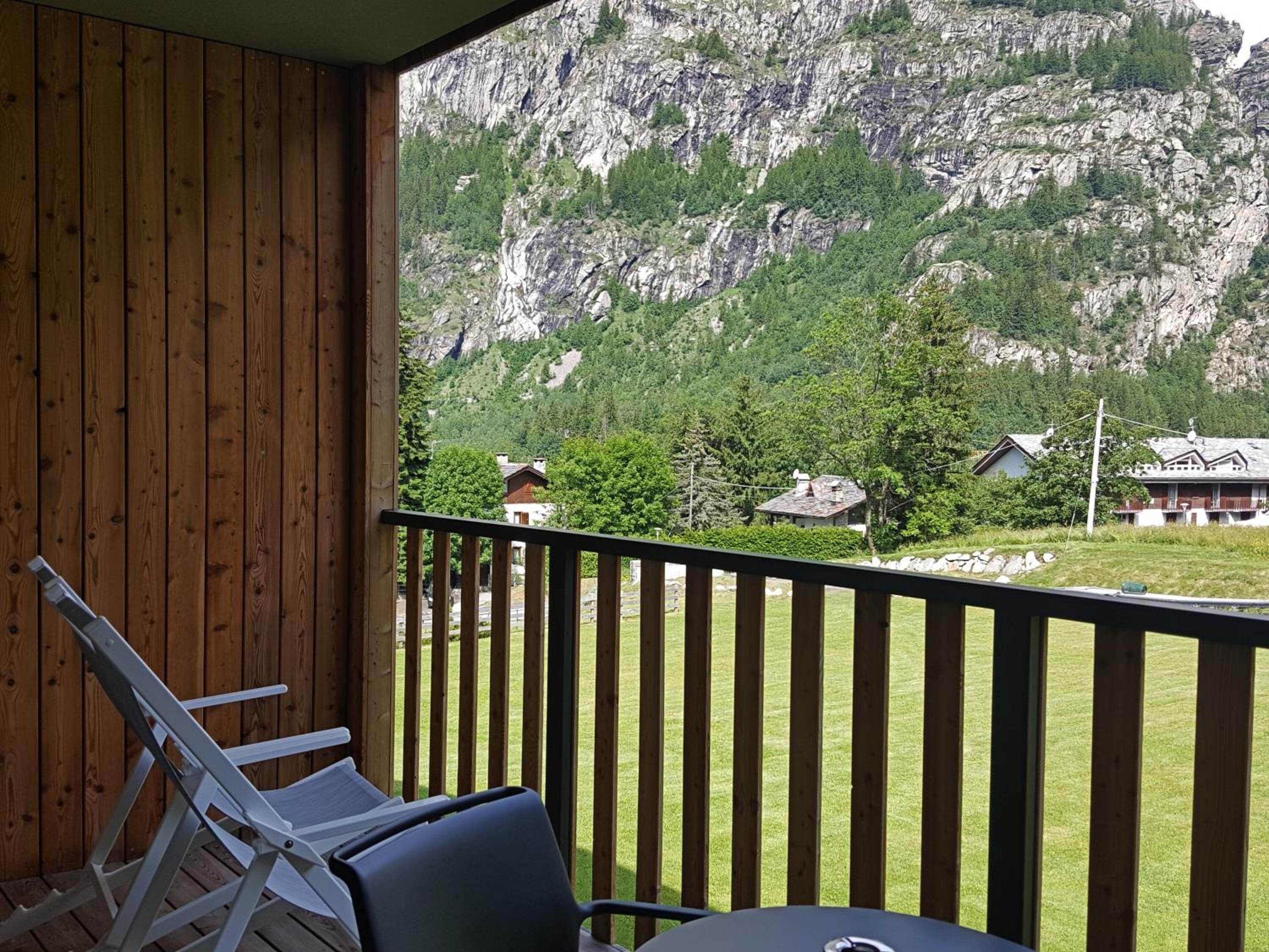 A balcony with a view of a mountainous landscape and several houses.
