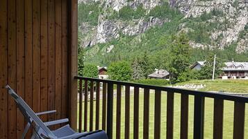 A balcony with a view of a mountainous landscape and several houses.