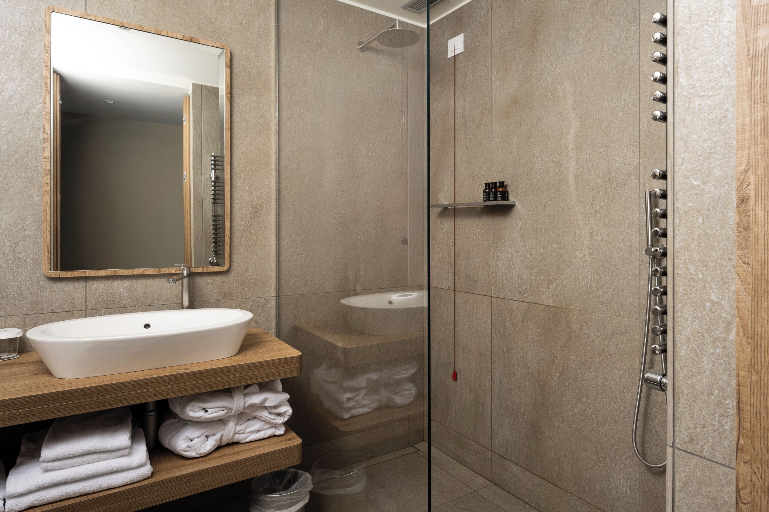 A modern bathroom with a freestanding sink, a mirror, a shower enclosure, and a towel rack.