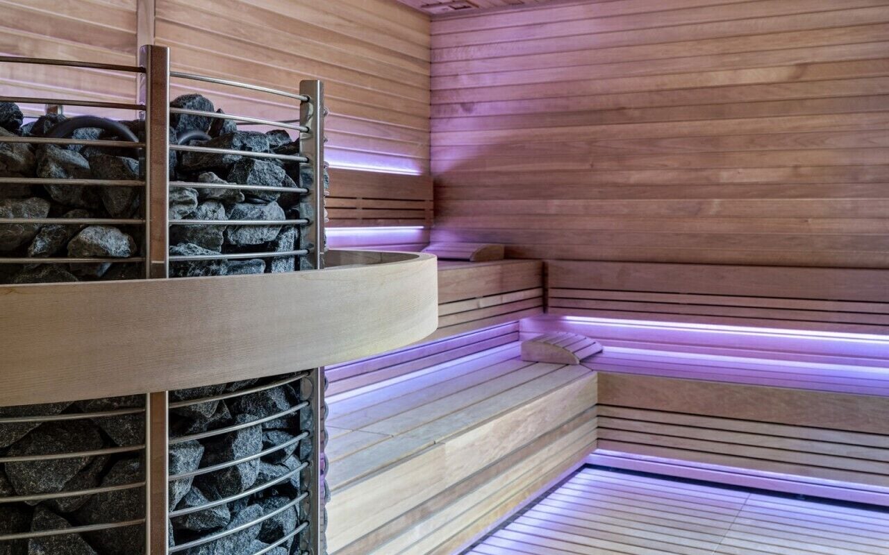 A sauna with wooden walls, a bench, and a stone shelf.