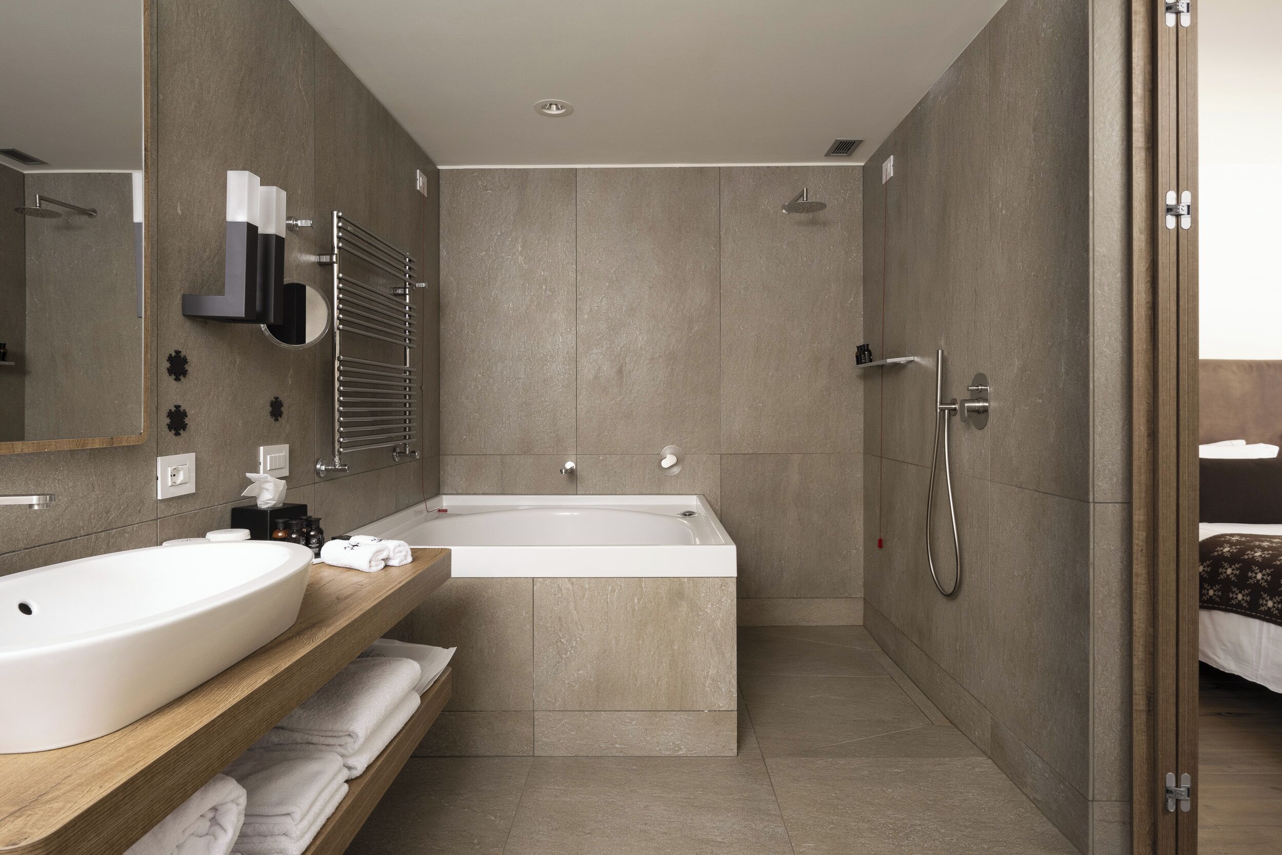 A modern bathroom with a freestanding bathtub, a large mirror, and a wooden vanity.