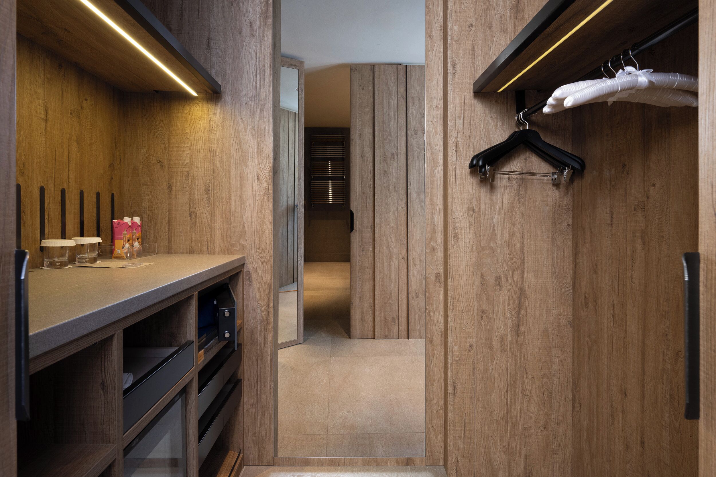 A modern walk-in closet with wooden paneling, a hanging rack, and a mirror.