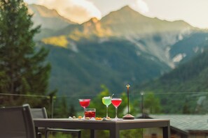 A table with three colorful drinks and a small lamp, set against a mountain backdrop. - Grand Hotel Courmayeur Montblanc by R Collection Hotels (Courmayeur)