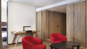 Una habitación moderna con un escritorio de madera, dos sillas rojas y una mesa negra.