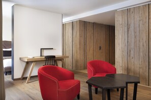 A modern room with a wooden desk, two red chairs, and a black table. - Grand Hotel Courmayeur Montblanc by R Collection Hotels (Courmayeur)