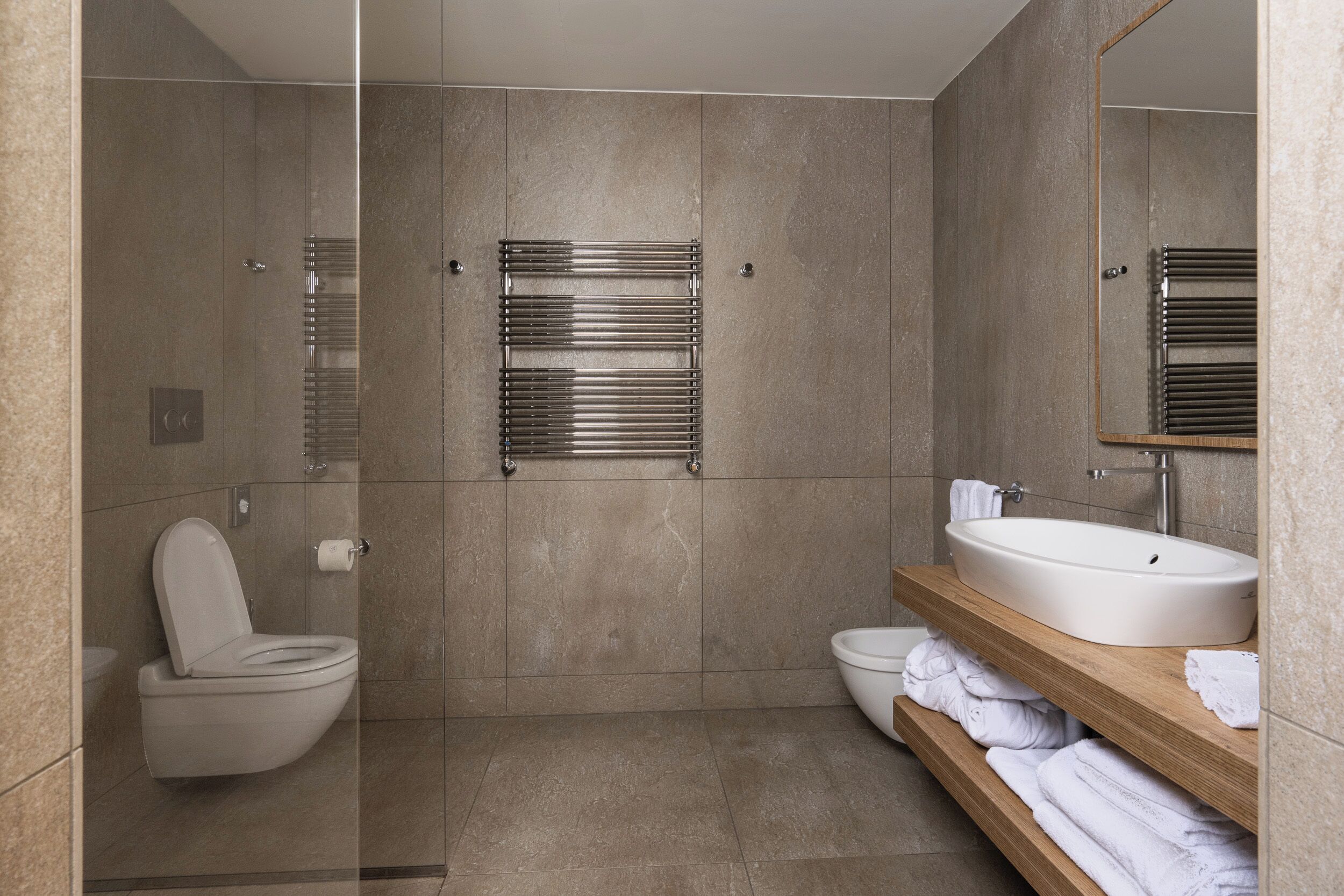 A modern bathroom with a glass-enclosed shower, a toilet, a sink, and a mirror.
