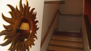 A staircase with wooden steps and a sunburst mirror on the wall. - Hôtel Saint Jean (Bourges)