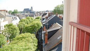 A view from a balcony overlooking a row of houses with a mix of architectural styles, including a modern building in the distance. - Hôtel Saint Jean (Bourges)