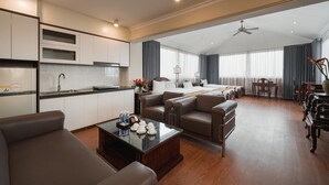 A modern hotel room with a kitchen, a living area with leather sofas, a dining table, and a large window with curtains. - Hanoi Little Town Hotel (Hanoi)