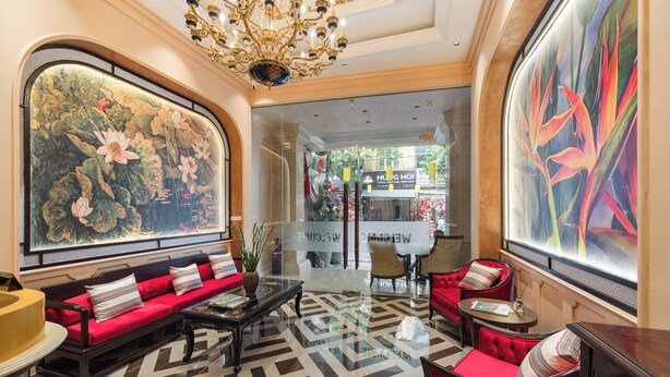 A lobby with a red sofa set, a chandelier, and large floral artwork on the walls. - Hanoi Little Town Hotel (Hanoi)
