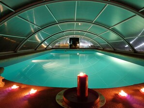 Una piscina interior con techo curvo y una vela central.