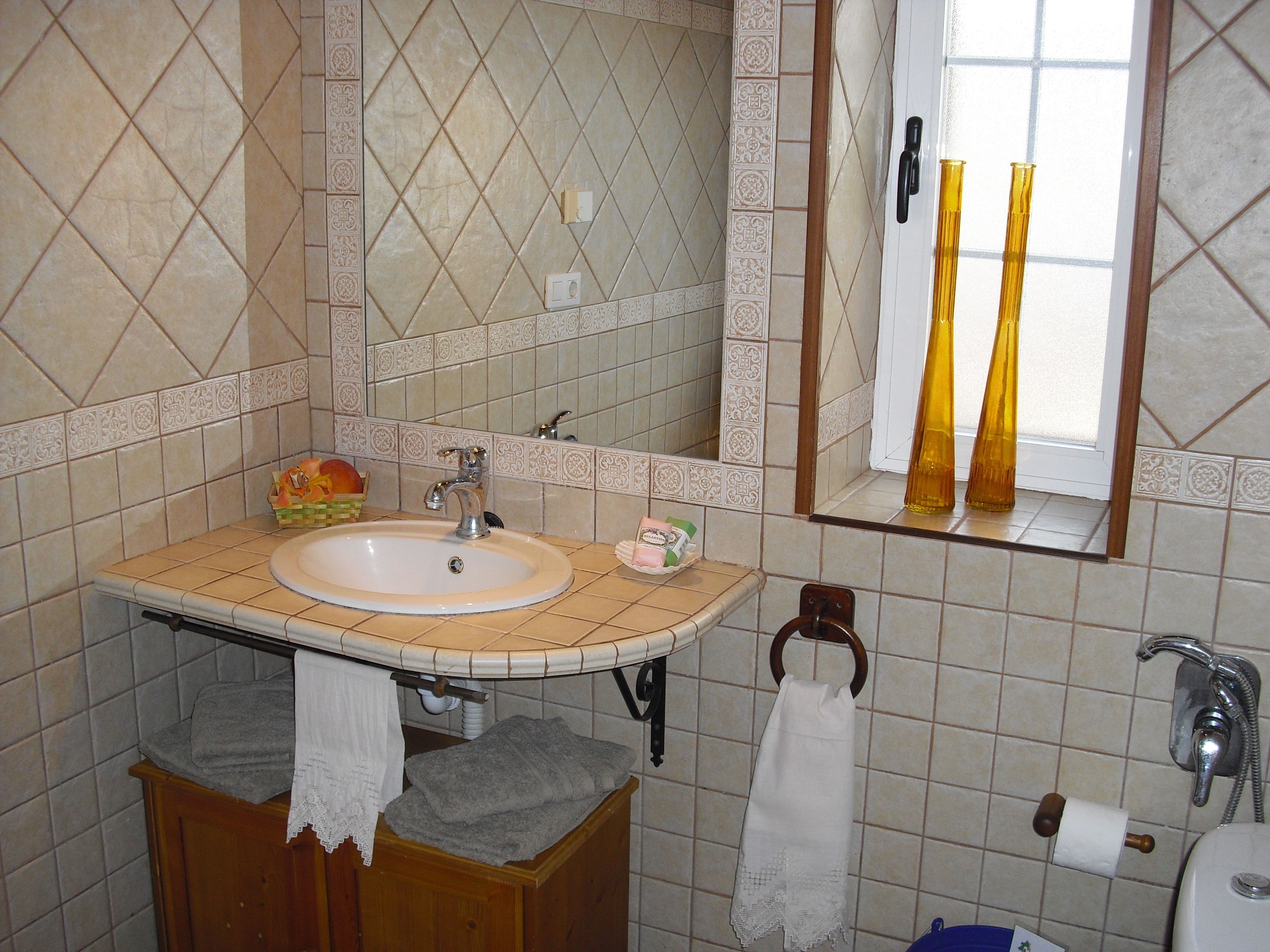 Een badkamer met een wastafel, spiegel, handdoekhouder en toilet.