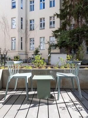 A terrace with two chairs and a table, a building in the background, and a bicycle. - Hotel Alt-Tempelhof (Berlin)