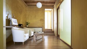 Ein Flur mit Holzboden, einem weißen Sofa, einem kleinen Tisch und einem Blumentopf.