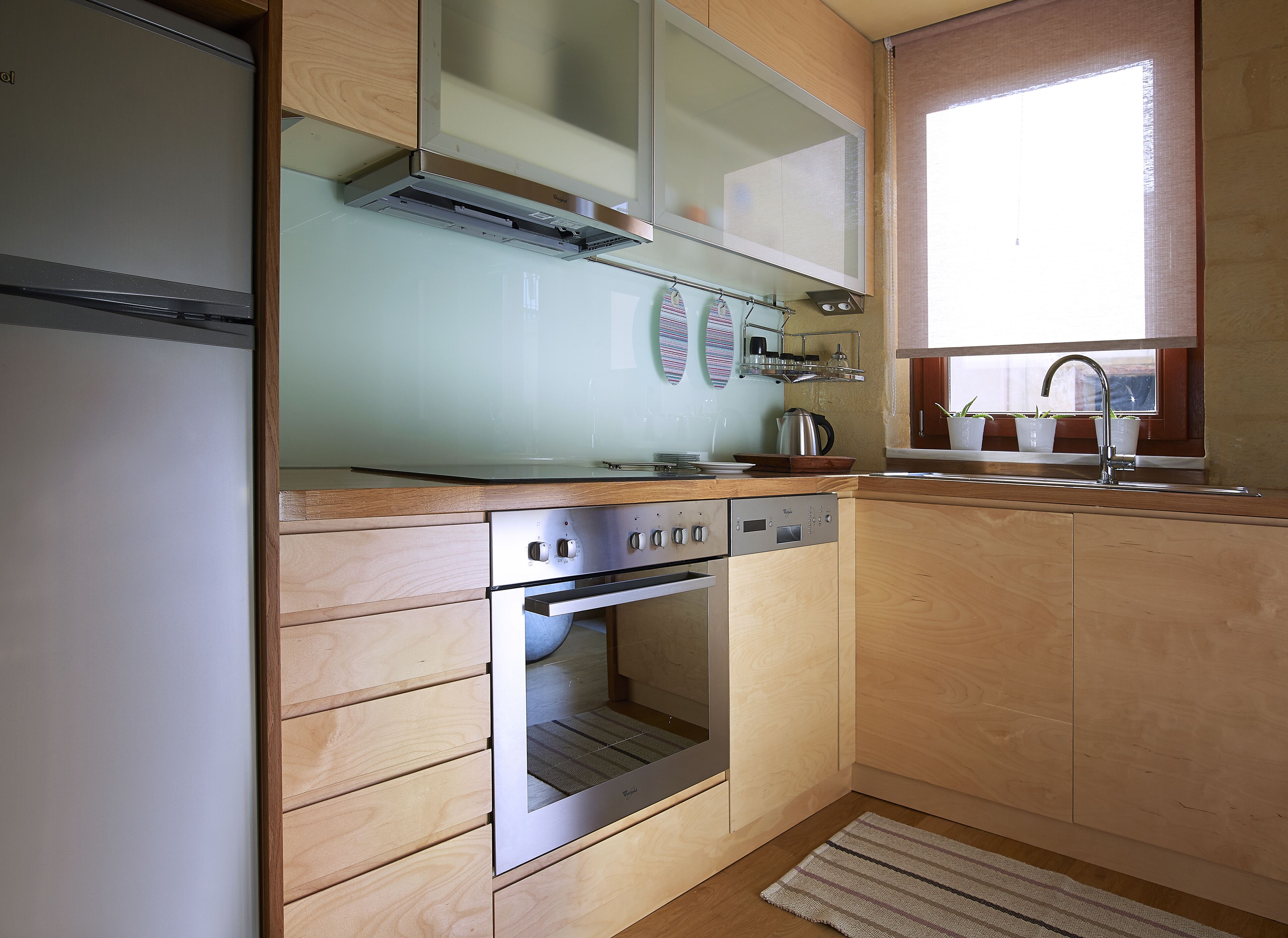 Una cocina con armarios de madera, electrodomésticos de acero inoxidable y una ventana con plantas en macetas.