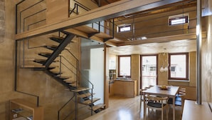Ein geräumiges Loft mit einer Holztreppe, einem Essbereich und einer Küche.