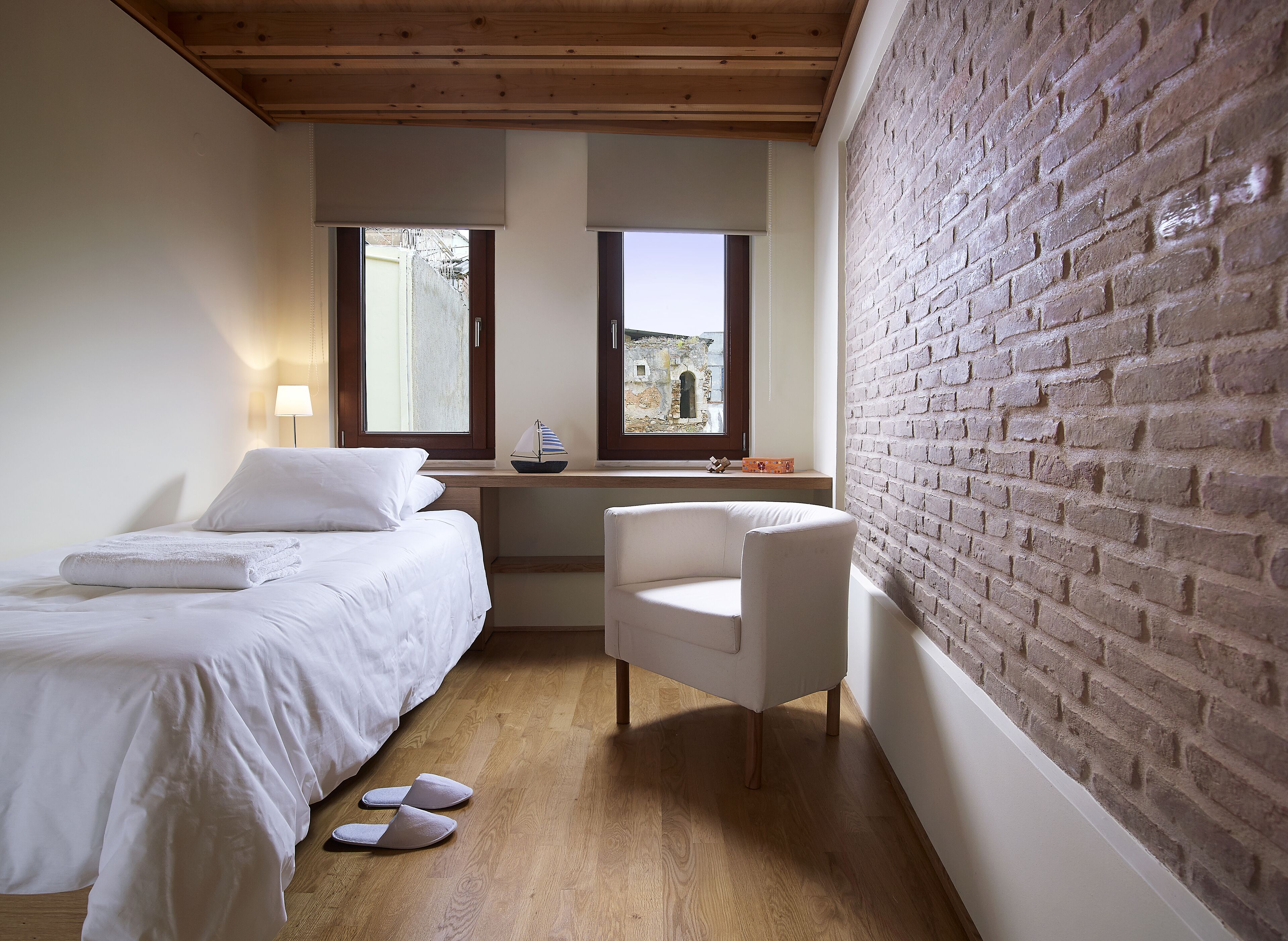 Ein Schlafzimmer mit Bett, Schreibtisch, Stuhl und einer Ziegelwand.
