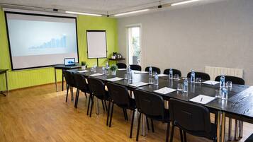 A conference room with a long table, chairs, a projector screen, and a whiteboard.