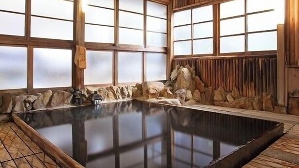 A traditional wooden bathhouse with a large hot spring, wooden beams, and stone walls. - Azumaya (Tanabe)