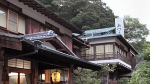 A traditional Japanese building with a wooden exterior, a tiled roof, and a stone pathway leading to the entrance. - Azumaya (Tanabe)