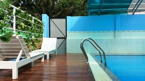 A swimming pool with a wooden deck, a metal ladder, and a white lounge chair. - Galaxy Hotel Phu Quoc (Phu Quoc)