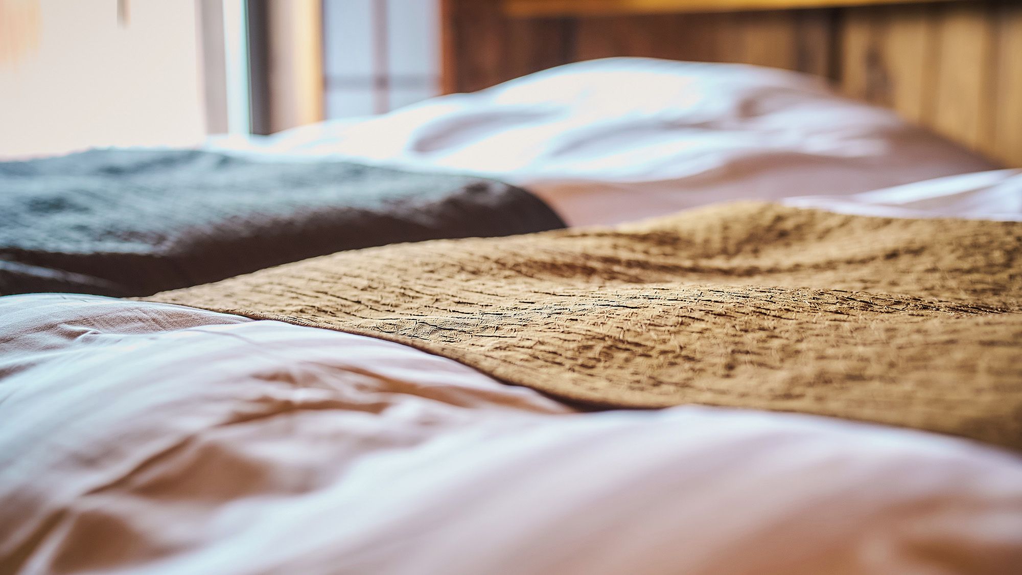 Una cama con una colcha texturizada y una almohada.